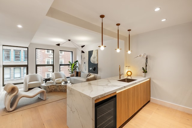 kitchen featuring wine cooler, a sink, light wood finished floors, modern cabinets, and recessed lighting