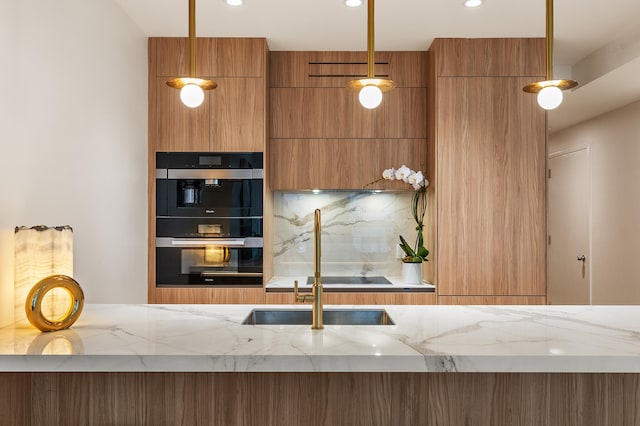 kitchen featuring brown cabinetry, light stone counters, a sink, and recessed lighting