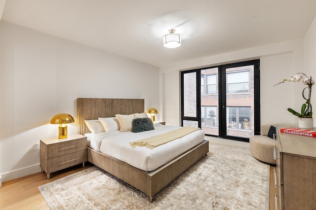 bedroom featuring light wood-type flooring, access to outside, and baseboards