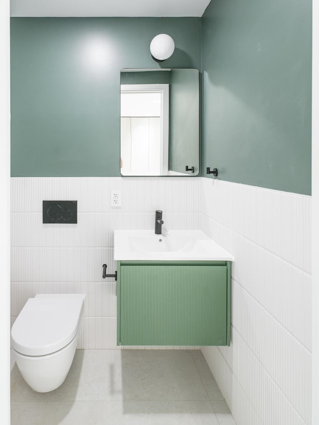 bathroom with tile walls, vanity, toilet, and wainscoting