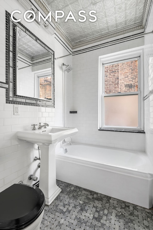 306 W 4th St Unit D3, New York City, NY 10014 - full bath with an ornate ceiling, washtub / shower combination, toilet, tile walls, and tile patterned floors