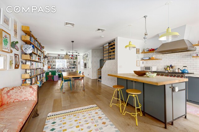 113A Columbia St, New York City, NY 11201 - kitchen with wooden counters, light wood-style floors, backsplash, island range hood, and a breakfast bar area