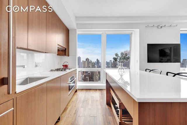 kitchen featuring stainless steel appliances, light countertops, light wood-style floors, modern cabinets, and range hood