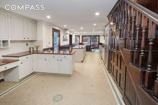 kitchen with a peninsula, a sink, recessed lighting, decorative backsplash, and dark countertops