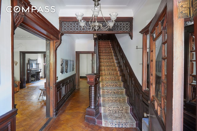 staircase featuring a chandelier, a towering ceiling, and crown molding