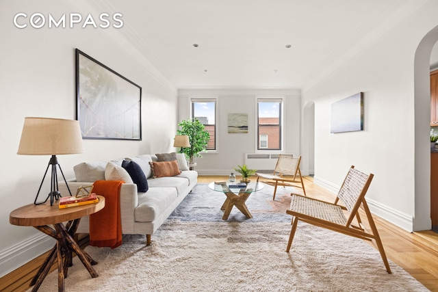 living area with arched walkways, baseboards, and ornamental molding