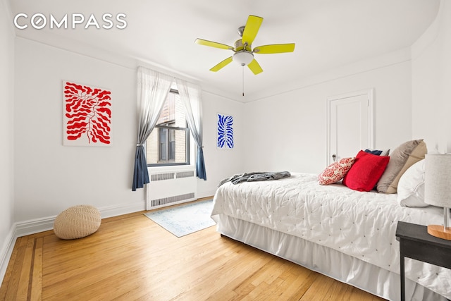 bedroom featuring radiator heating unit, wood finished floors, baseboards, and ceiling fan