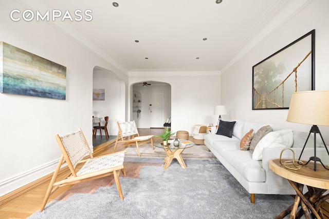 living area featuring arched walkways, ornamental molding, wood finished floors, and baseboards