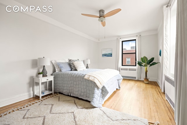 bedroom with radiator heating unit, light wood-style flooring, and baseboards