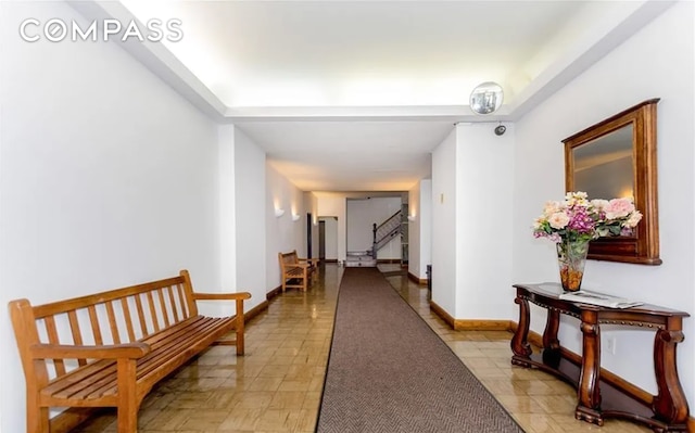 corridor with stairway, baseboards, and light tile patterned flooring