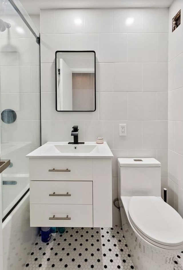 full bathroom with tile walls, vanity, toilet, and  shower combination