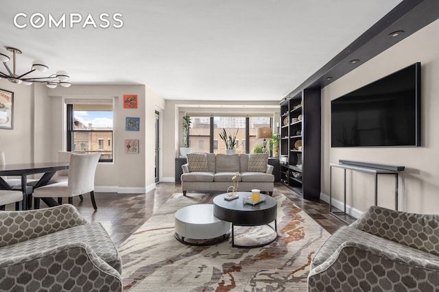living room featuring wood finished floors, plenty of natural light, baseboards, and a chandelier