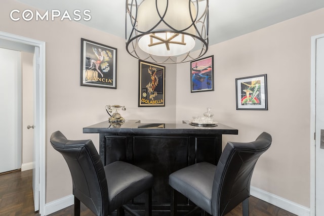 dining room featuring a bar and baseboards