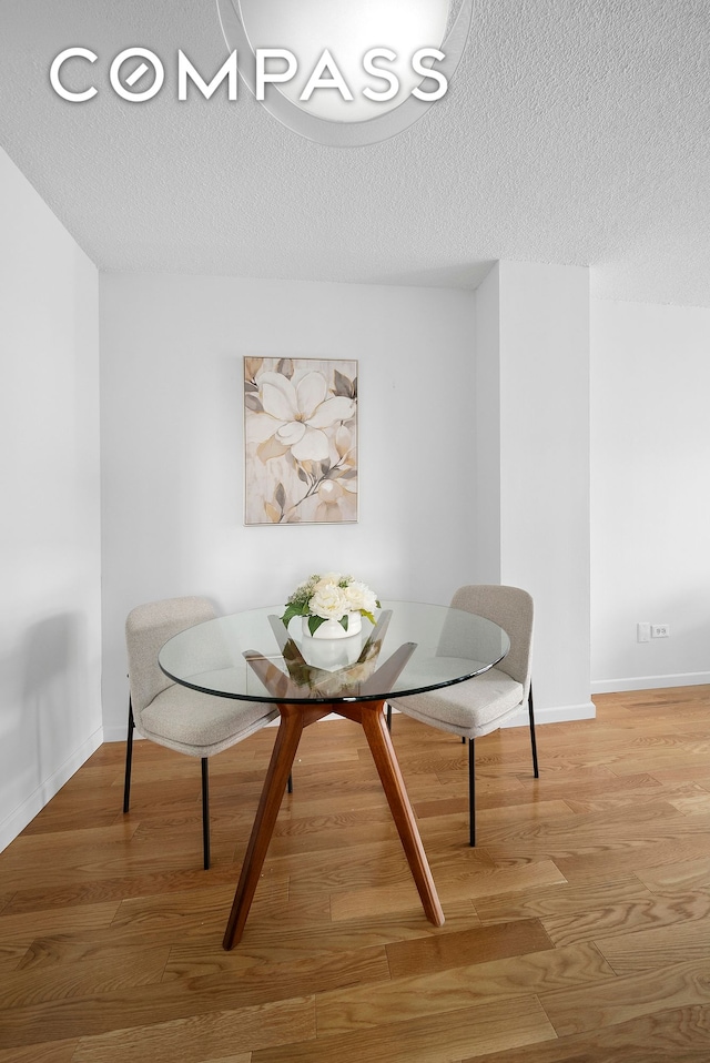 178 E 80th St Unit 5D, New York City, NY 10075 - dining room featuring wood finished floors, a textured ceiling, and baseboards