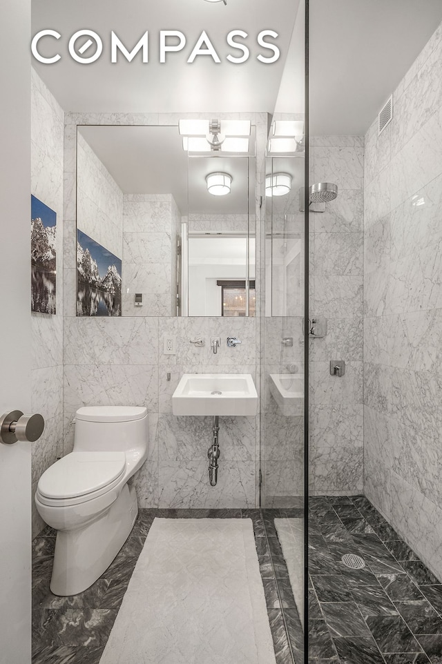 24 5th Ave Unit 824, New York City, NY 10011 - bathroom featuring a sink, toilet, marble finish floors, tiled shower, and tile walls