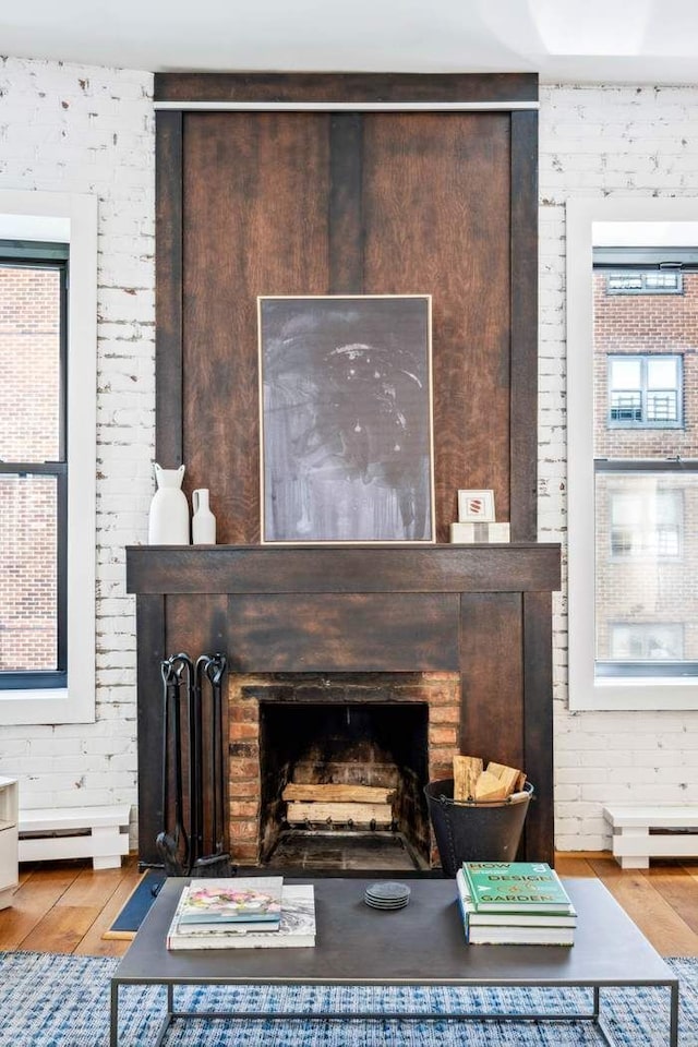 detailed view of wood finished floors, a large fireplace, and baseboard heating