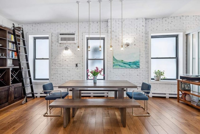dining space featuring a wall unit AC, hardwood / wood-style flooring, and brick wall