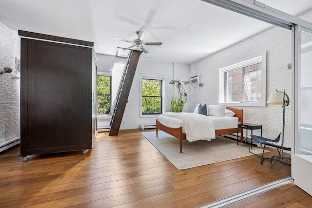 bedroom featuring multiple windows, hardwood / wood-style floors, brick wall, a baseboard radiator, and a wall mounted air conditioner