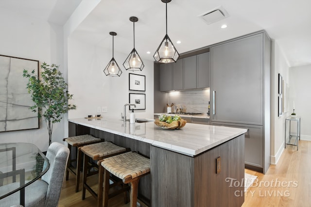 kitchen featuring gray cabinets, a sink, a breakfast bar area, a peninsula, and recessed lighting