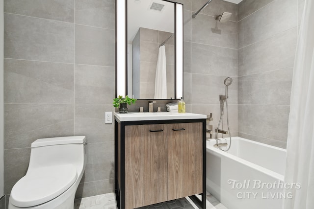 full bath featuring tile walls, toilet, vanity, and shower / bath combo