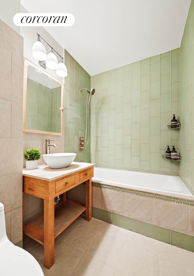 full bathroom featuring tile walls, tiled shower / bath, tile patterned flooring, toilet, and vanity