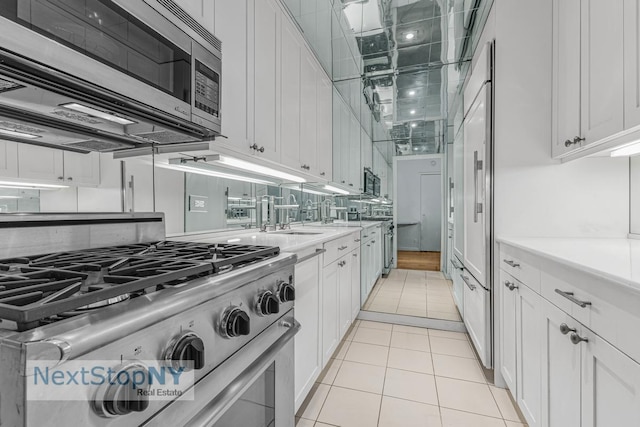 kitchen with appliances with stainless steel finishes, white cabinets, light countertops, and a sink