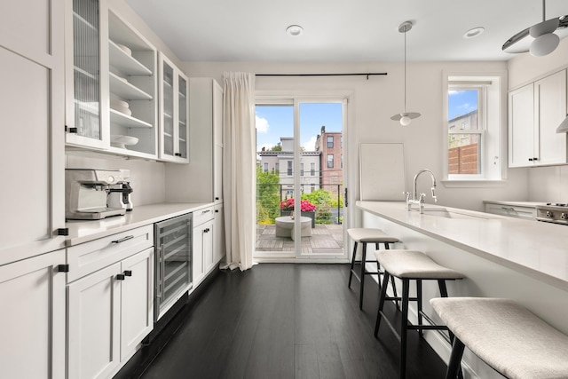 481 Macon St, New York City, NY 11233 - kitchen featuring wine cooler, a kitchen breakfast bar, white cabinetry, glass insert cabinets, and light countertops