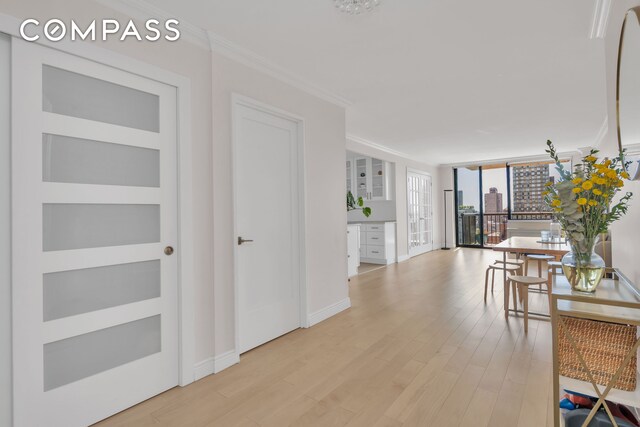 171 E 84th St Unit 22C, New York City, NY 10028 - hallway with crown molding, light wood finished floors, baseboards, and floor to ceiling windows