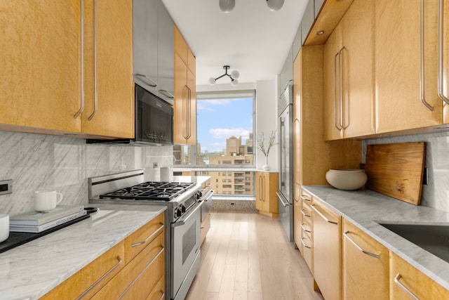 kitchen featuring stainless steel appliances, backsplash, light stone counters, and light wood-style floors
