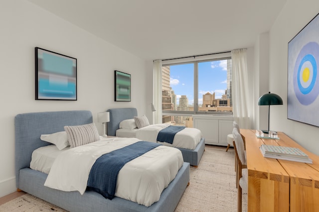 bedroom with light wood finished floors and a view of city