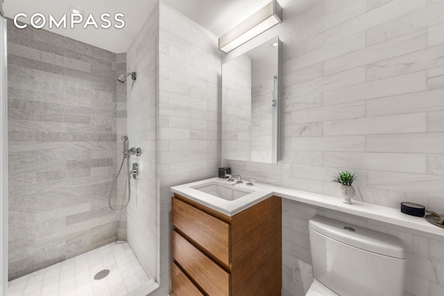 bathroom with tiled shower, toilet, vanity, tasteful backsplash, and tile walls