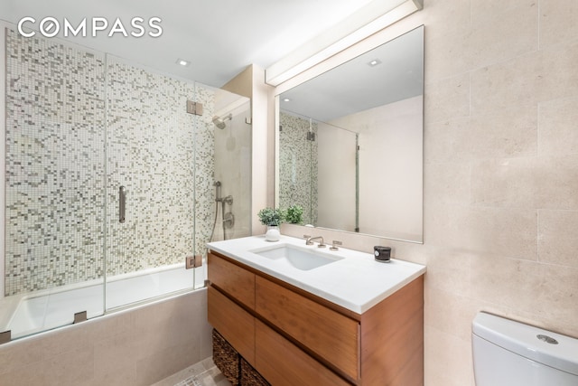 bathroom with toilet, vanity, and tiled shower / bath