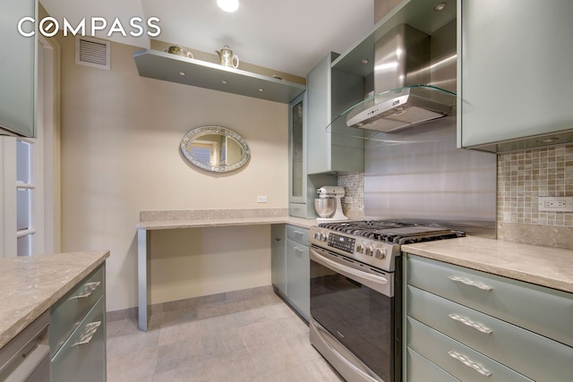 201 E 80th St Unit 16D, New York City, NY 10075 - kitchen with stainless steel range with gas cooktop, wall chimney exhaust hood, gray cabinetry, backsplash, and baseboards