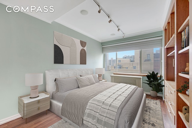 201 E 80th St Unit 16D, New York City, NY 10075 - bedroom featuring track lighting, radiator, wood finished floors, crown molding, and baseboards