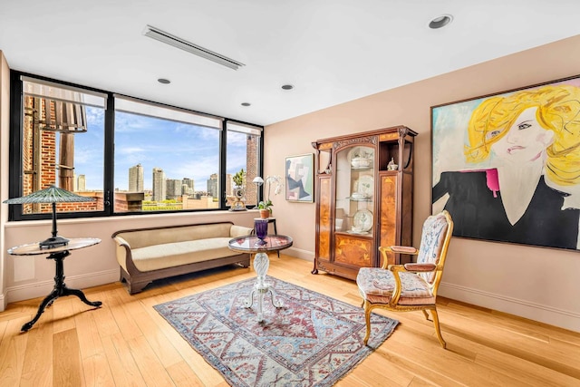 living area featuring baseboards, a skyline view, wood finished floors, and recessed lighting