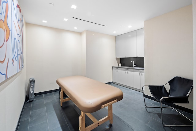 living area featuring recessed lighting, bar with sink, and baseboards