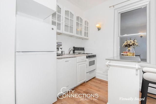 223 E 50th St Unit 2-C, New York City, NY 10022 - kitchen with white appliances, glass insert cabinets, light wood-style flooring, white cabinetry, and light countertops