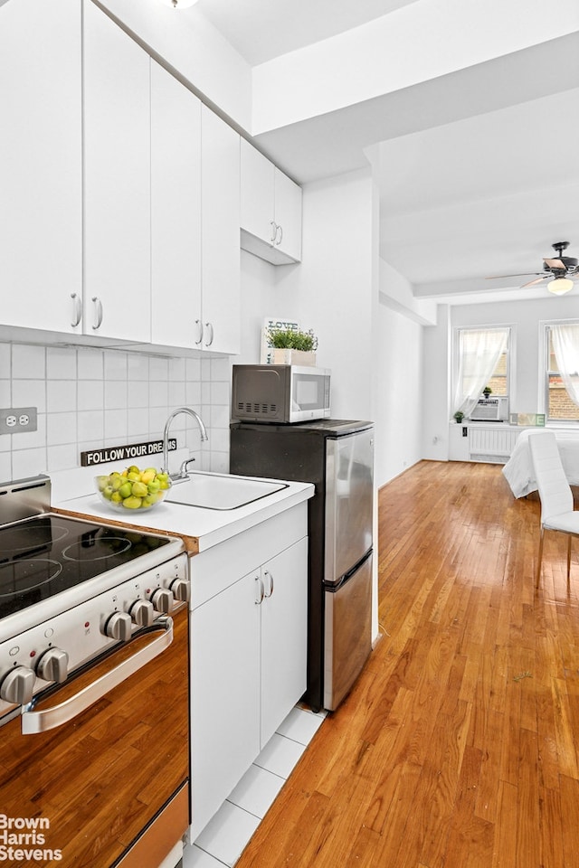310 Riverside Dr Unit 1201, New York City, NY 10025 - kitchen with white appliances, light wood-type flooring, white cabinetry, and backsplash