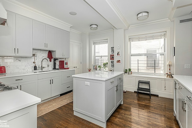 kitchen with a sink, decorative backsplash, ornamental molding, dark wood-type flooring, and light countertops