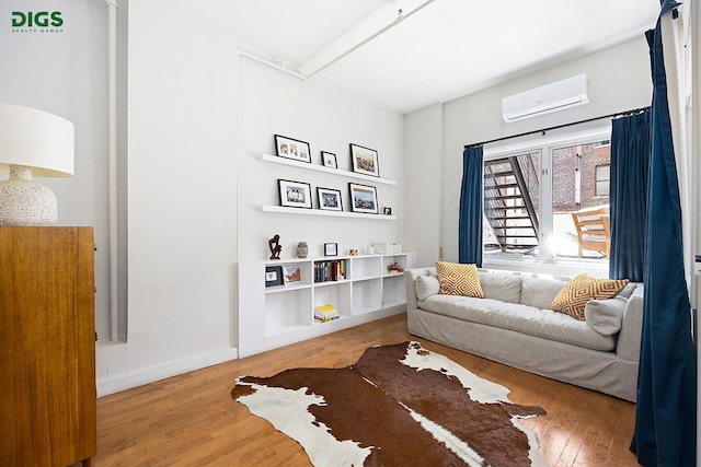 sitting room with an AC wall unit and wood finished floors