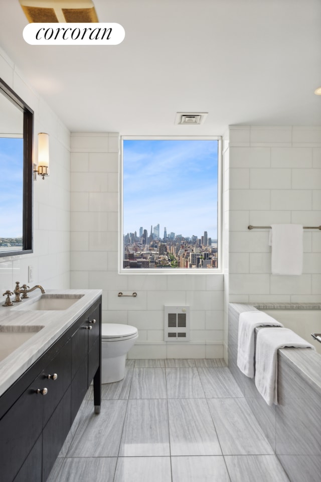 bathroom with a view of skyline, tile walls, plenty of natural light, toilet, and heating unit