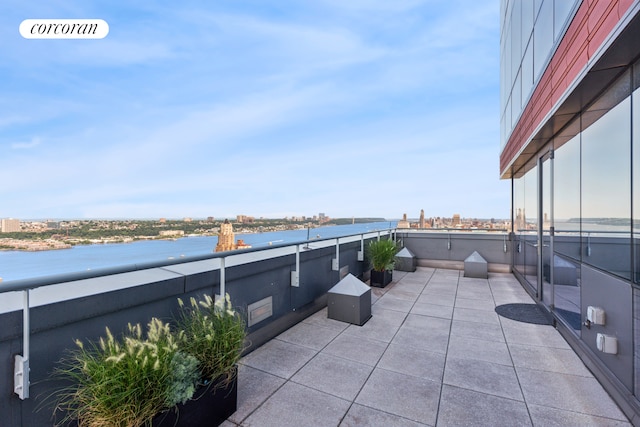 view of patio with a balcony, a water view, and a city view