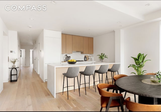 96 N 1st St Unit 3A, New York City, NY 11249 - kitchen featuring modern cabinets, light brown cabinetry, light wood-style flooring, a kitchen bar, and light countertops