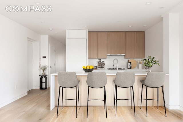 96 N 1st St Unit 3A, New York City, NY 11249 - kitchen featuring light wood finished floors, light countertops, a peninsula, and a breakfast bar