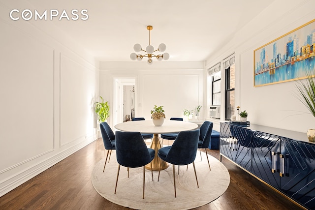 dining space with dark wood-style floors, a chandelier, and a decorative wall