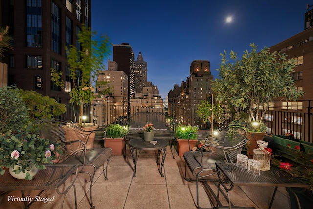 patio at night with a view of city lights and fence