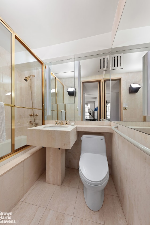 full bathroom with tile walls, tiled shower / bath combo, tile patterned flooring, and toilet