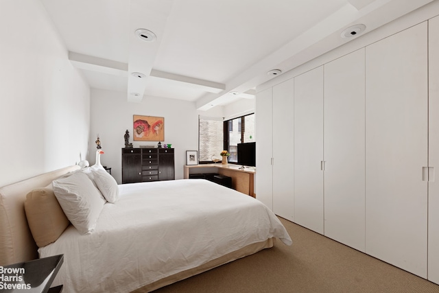 bedroom with beamed ceiling and light colored carpet