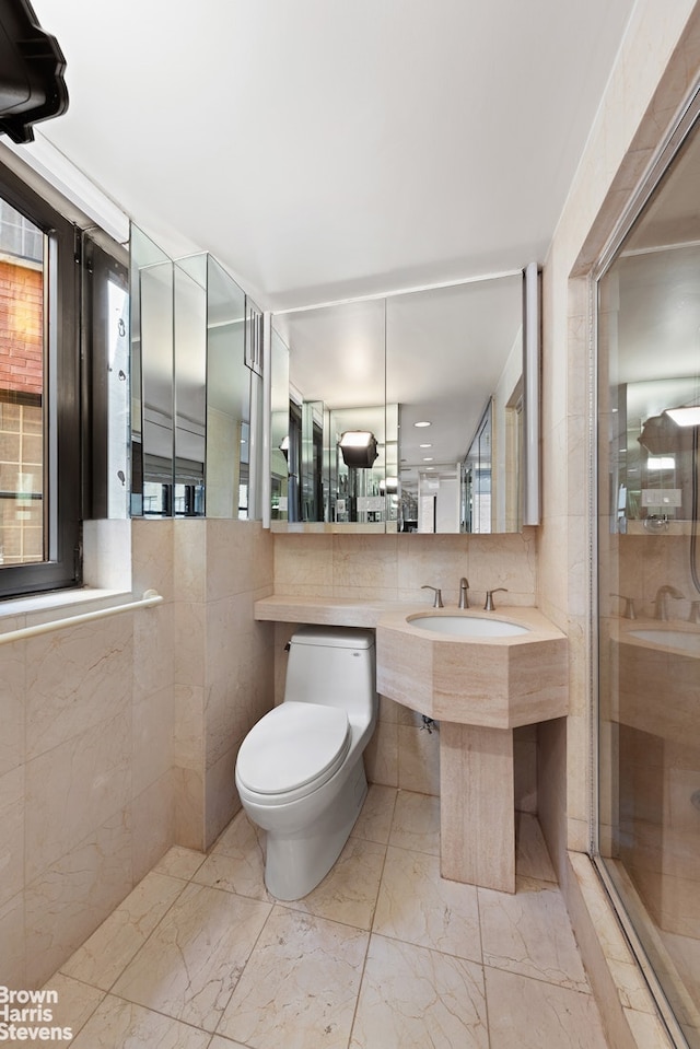 750 Park Ave Unit 9Cd, New York City, NY 10021 - bathroom with toilet, tile walls, marble finish floors, a shower stall, and a sink