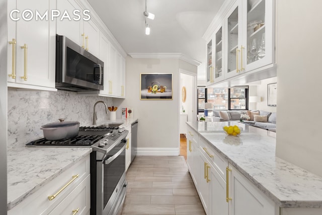 kitchen featuring appliances with stainless steel finishes, decorative backsplash, white cabinetry, baseboards, and light stone countertops